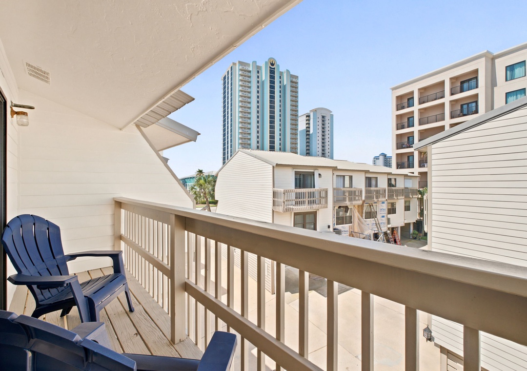 Step out onto your private balcony and soak in the coastal cityscape. A cozy seating area invites you to savor morning coffee or evening breezes, with views of nearby towers and tropical palms just beyond.