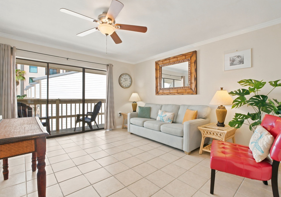 Settle into this bright, coastal-inspired living room where soft breezes from the ceiling fan and pops of color invite you to unwind after a day exploring nearby beaches.