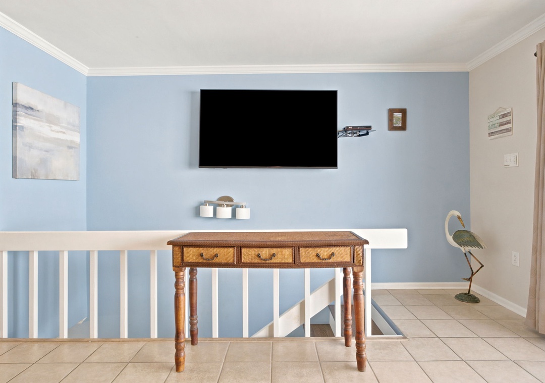 Your upstairs landing features a coastal-style console table, wall-mounted flat-screen TV, and charming beach decor—perfect for relaxing between spaces in your beach retreat.