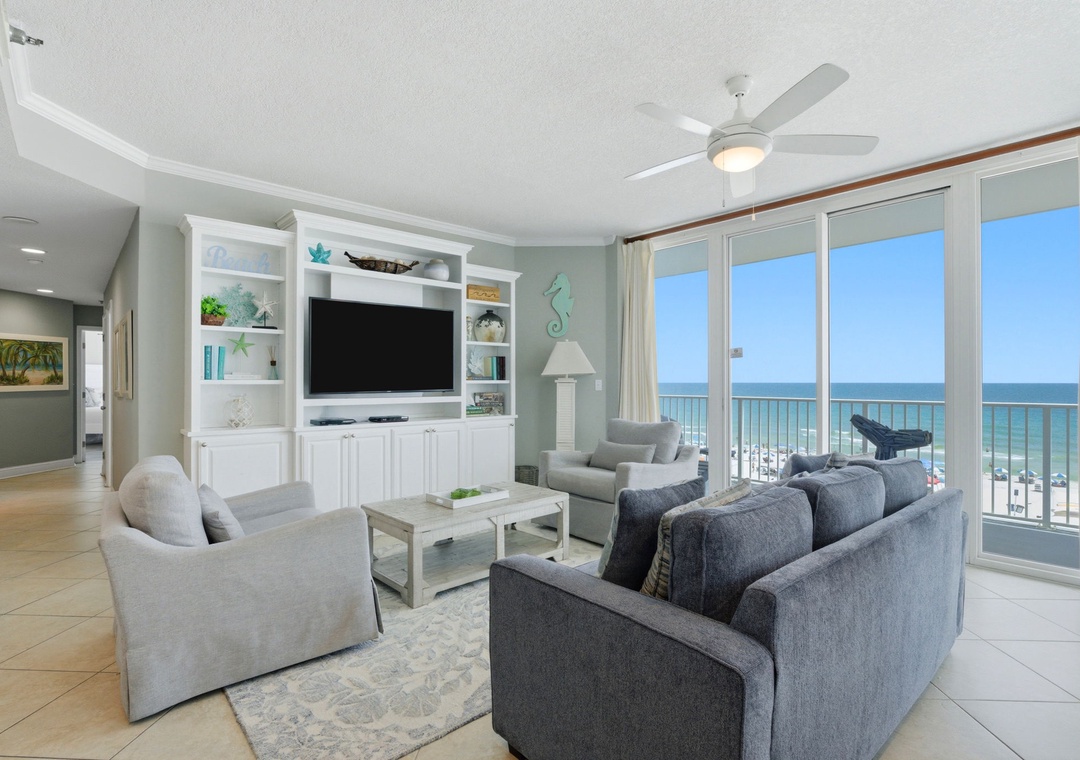 Lighthouse 418- Unwind in your bright, beach-themed living room where coastal decor and floor-to-ceiling windows frame endless ocean views. Relax on plush sofas, enjoy your favorite shows, and step onto your balcony to soak in the sea breeze.