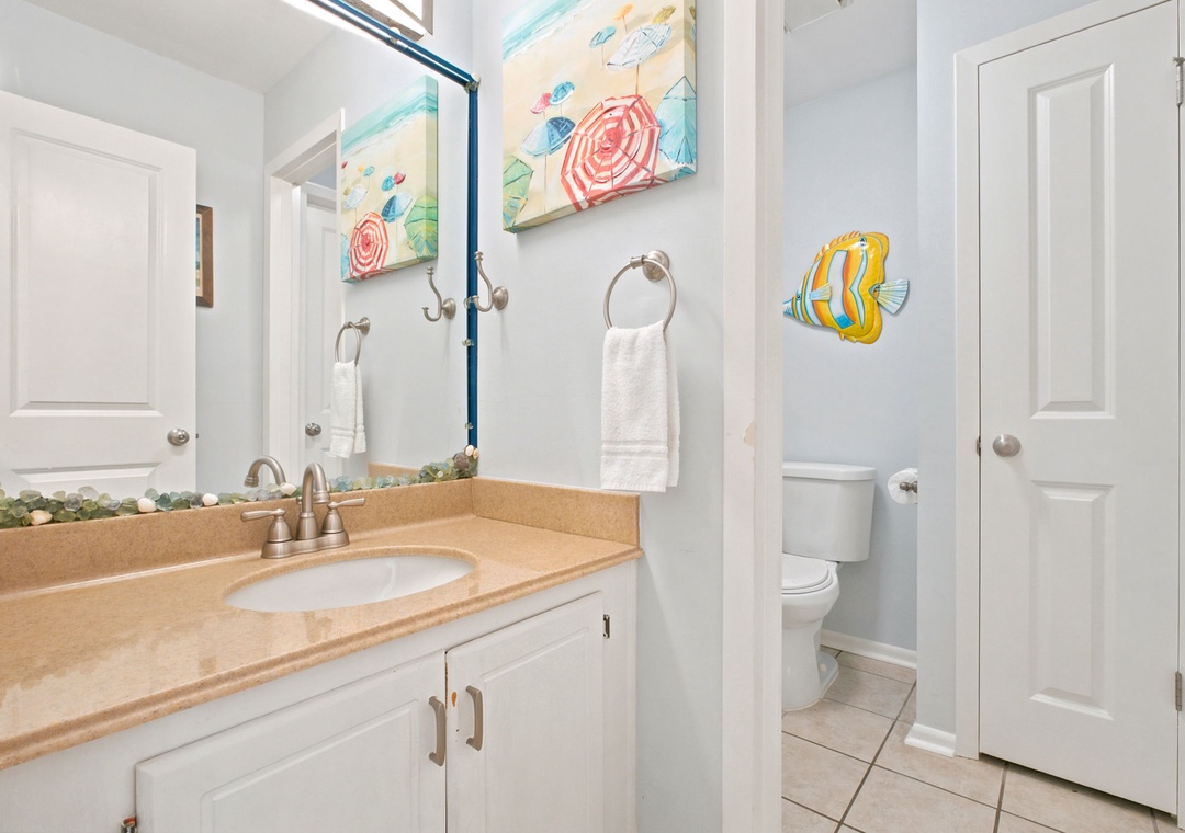 Your private coastal-inspired bathroom features fresh towels, a spacious vanity, and playful beach artwork to brighten your morning routine.
