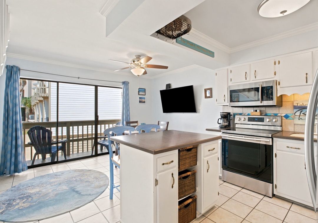 Gather around the island in this bright, coastal kitchen where cooking and conversation flow naturally. Stainless appliances, ocean-inspired accents, and a breezy balcony nearby set the stage for your beachside stay.