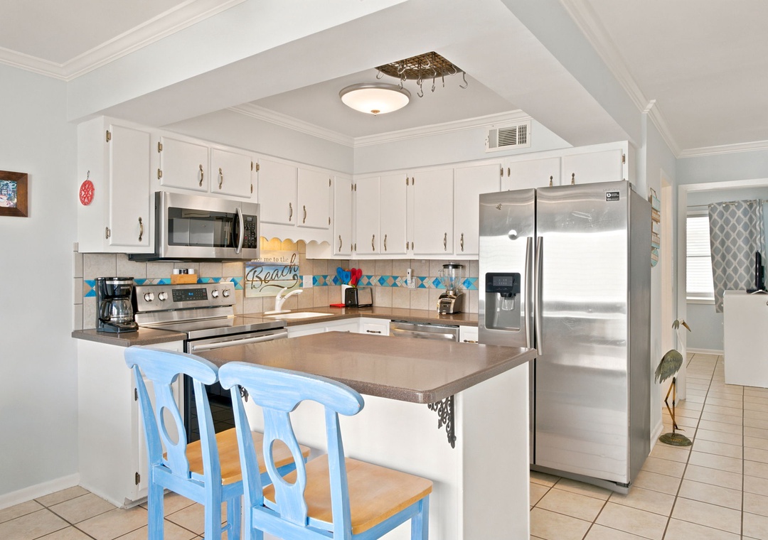 Your bright, fully equipped kitchen features modern stainless steel appliances and a welcoming breakfast bar where you can sip morning coffee before heading to the beach.