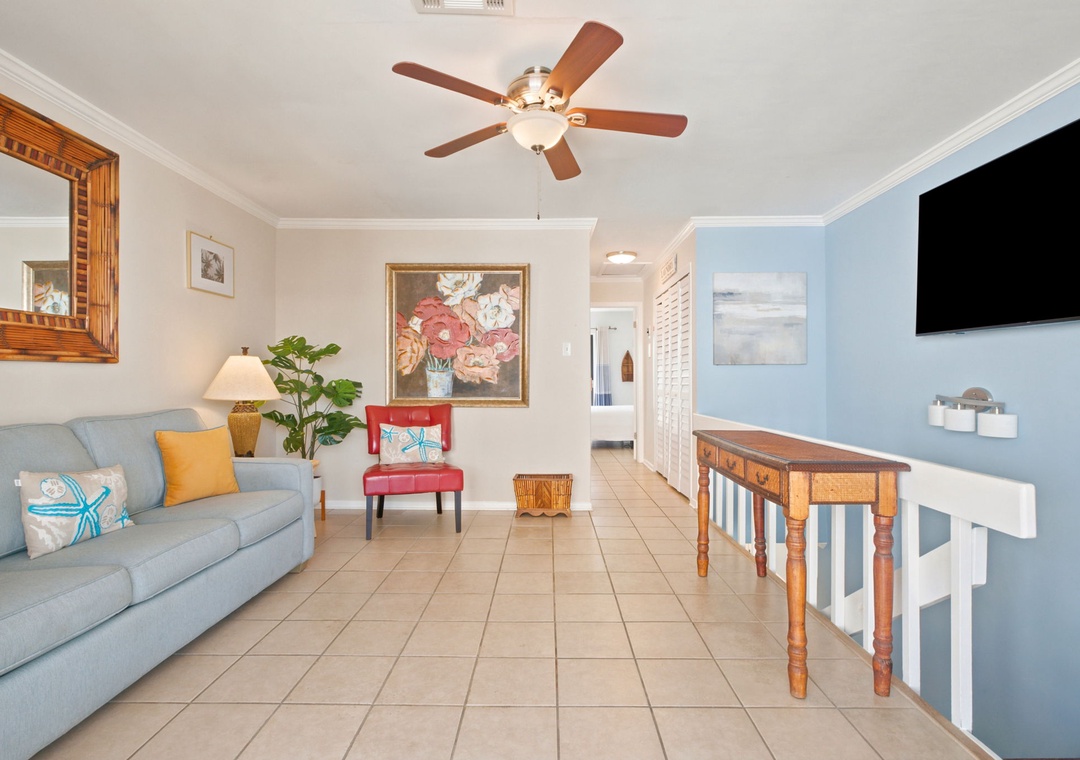 Unwind in your inviting living space, where coastal charm meets comfort. Sink into the plush sofa, enjoy the ceiling fan's gentle breeze, and feel right at home with cheerful artwork and modern entertainment at your fingertips.