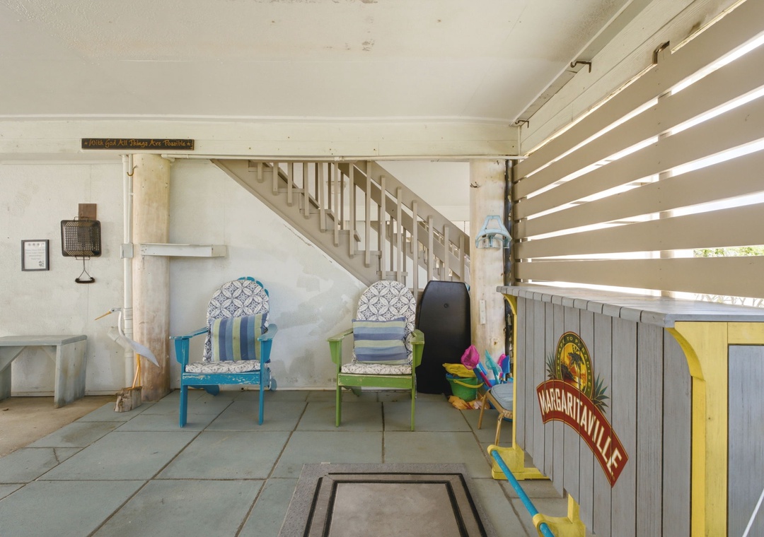 Covered outdoor space with colorful vintage chairs and beachy décor creates a relaxed spot to unwind after exploring. The bar setup adds fun island vibes to your stay.