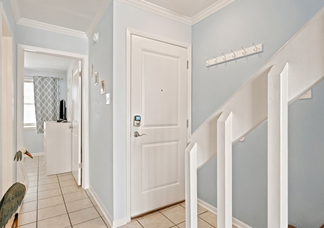 Step into a bright, welcoming entryway where soft blue walls and crisp white trim create a soothing first impression, with hooks ready for your coats and easy access to the rest of your home.