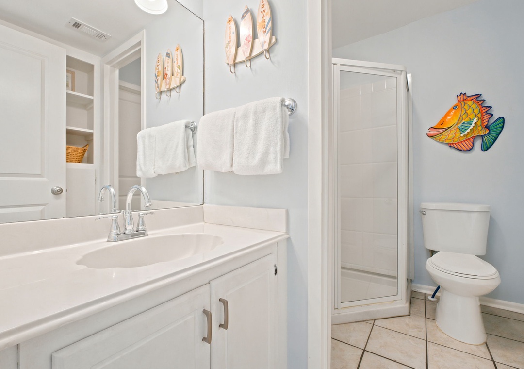 Freshen up in this cheerful bathroom with playful coastal decor, fluffy towels, and a spacious walk-in shower—your perfect post-beach retreat.