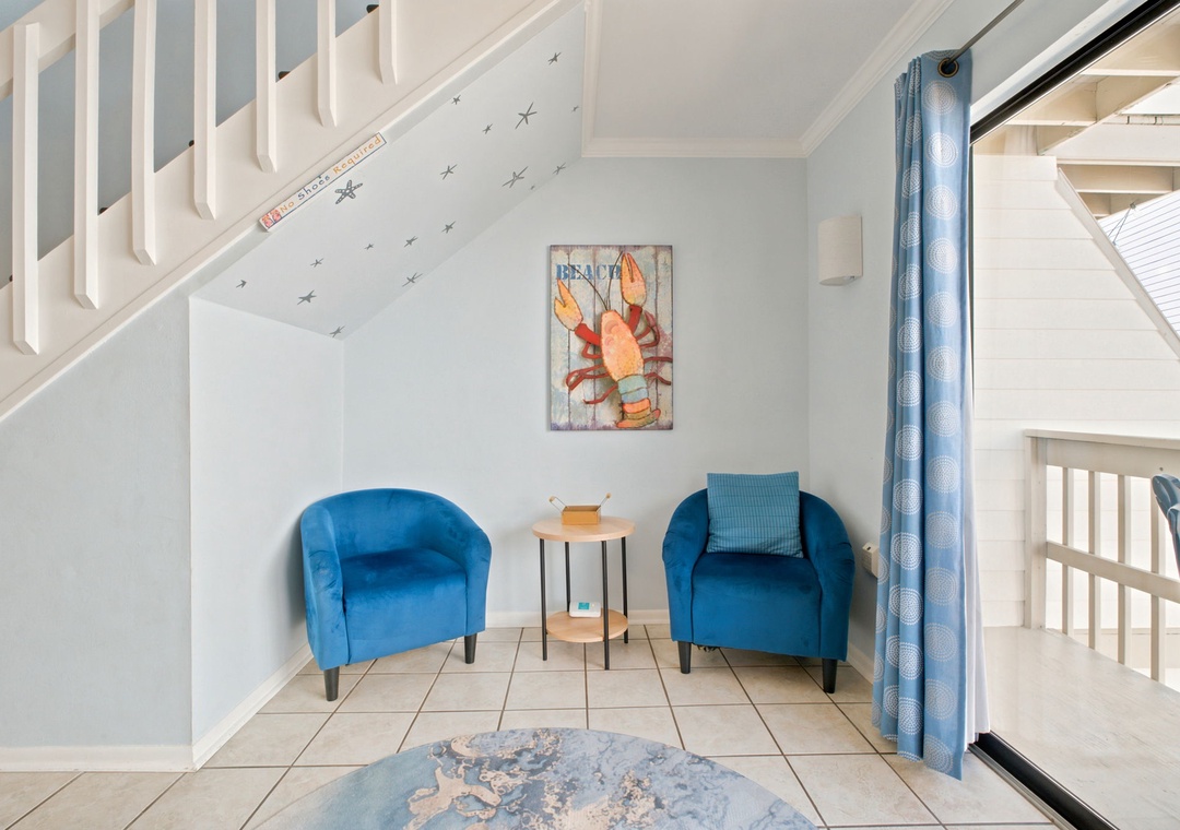 Sink into plush blue chairs in your private seating nook, where coastal art and soaring ceilings create a peaceful retreat for morning coffee or evening reflection.