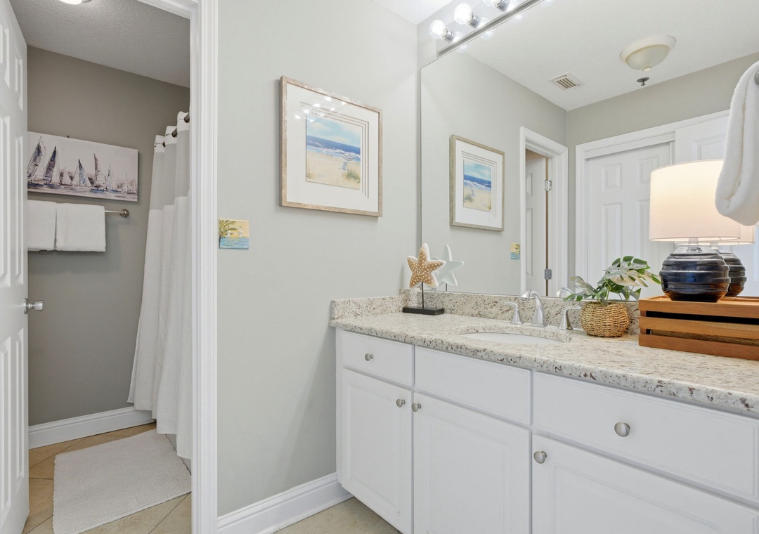 Lighthouse 418- Your private bathroom features a spacious vanity with granite countertops, coastal decor, and a peaceful palette. The shower awaits in a separate space for added privacy and convenience.