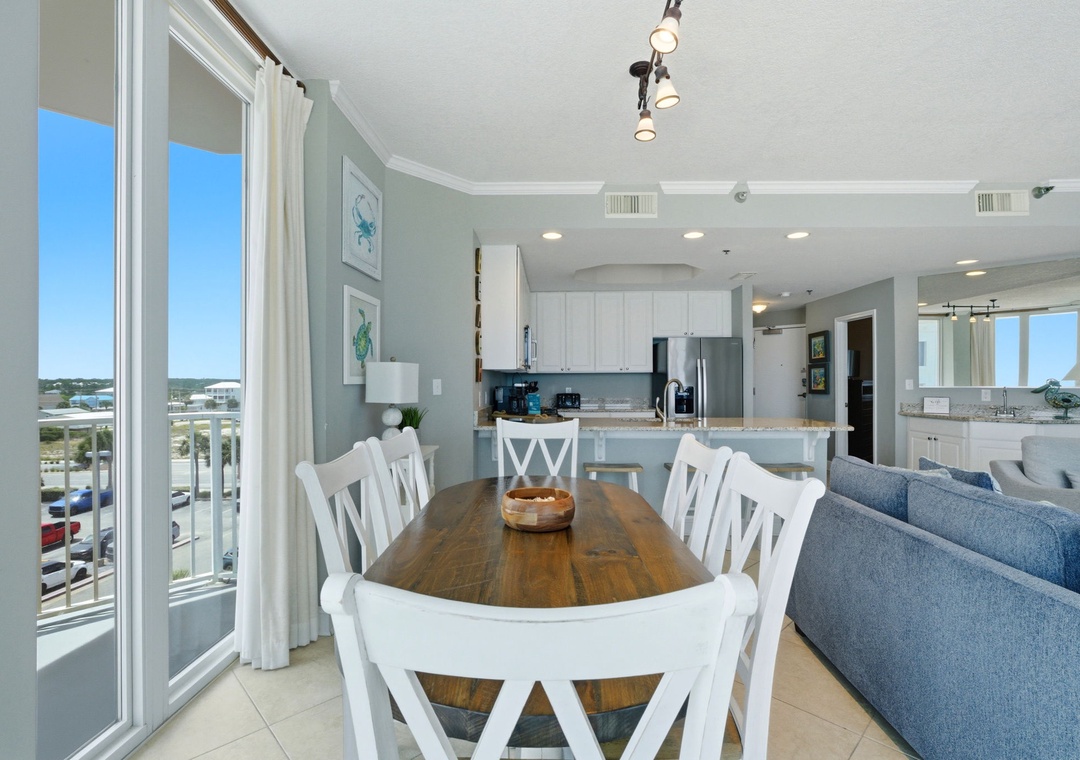 Lighthouse 418- Step into your bright coastal retreat where vaulted ceilings and soft tones welcome you home. Gather around the rustic wood table while sunlight pours through floor-to-ceiling glass doors framing views beyond.