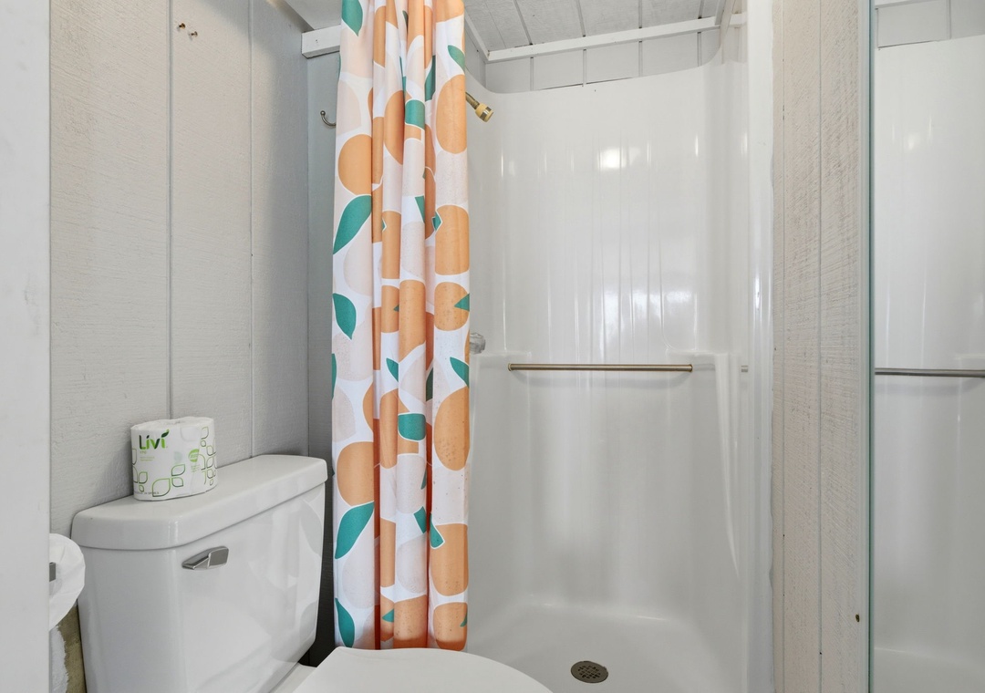 Seaswept- Bathroom 3 features a sleek walk-in shower with a cheerful curtain and modern amenities for a refreshing start to your day.