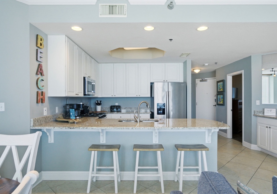 Lighthouse 418- Gather around this spacious kitchen featuring modern appliances, granite countertops, and a breakfast bar perfect for your morning coffee. The coastal palette and open layout invite you to feel right at home.