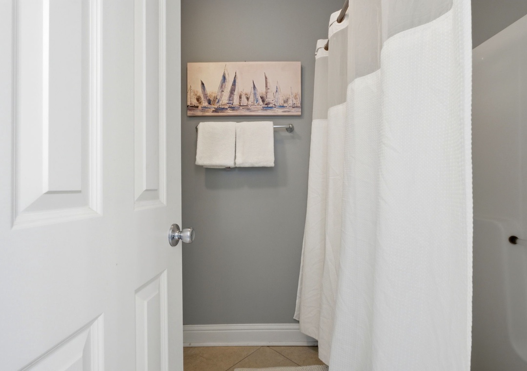 Lighthouse 418- Crisp linens and coastal touches await in your private bathroom, where soft towels and serene sailboat art set a relaxing, seaside tone.