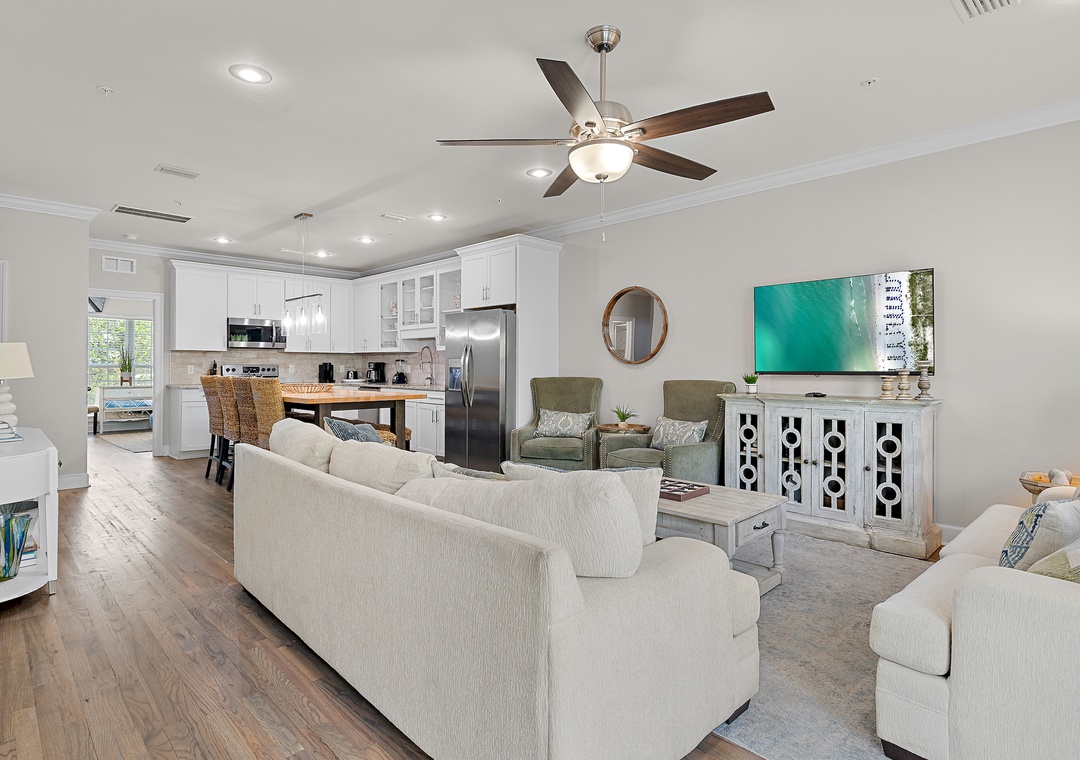 Open-concept living and dining with hardwood floors, plush seating, and a fully equipped kitchen — perfect for gathering after a day at the beach.