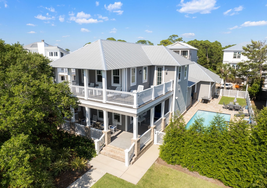 Spacious beach home with wraparound balconies and lush greenery.