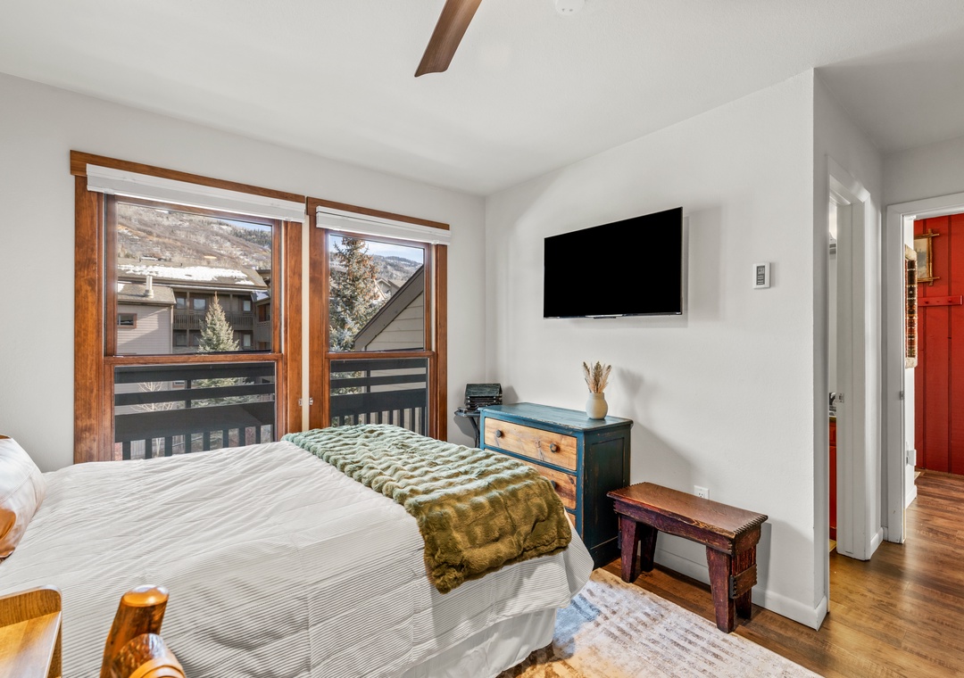 Relax in your cozy bedroom with mountain views, warm wood accents, and modern TV for perfect evenings after adventure-filled days.