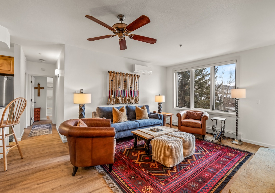 Unwind in your stylish living room with rich leather chairs, cozy sofa, and mountain views through oversized windows.