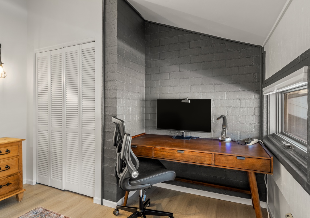 Your stylish workspace awaits with a sleek wooden desk, and an ergonomic chair, against striking gray brick walls.