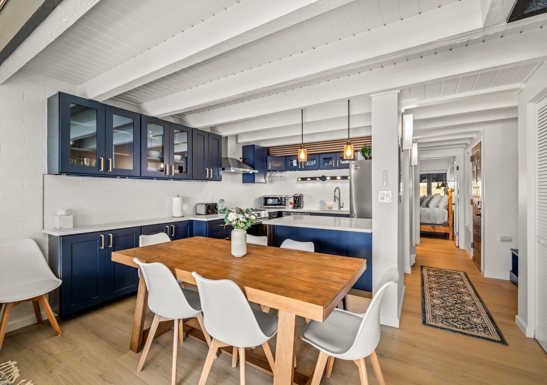 Your stylish open-plan kitchen features navy blue cabinets and a warm wooden dining table where you'll enjoy meals together.