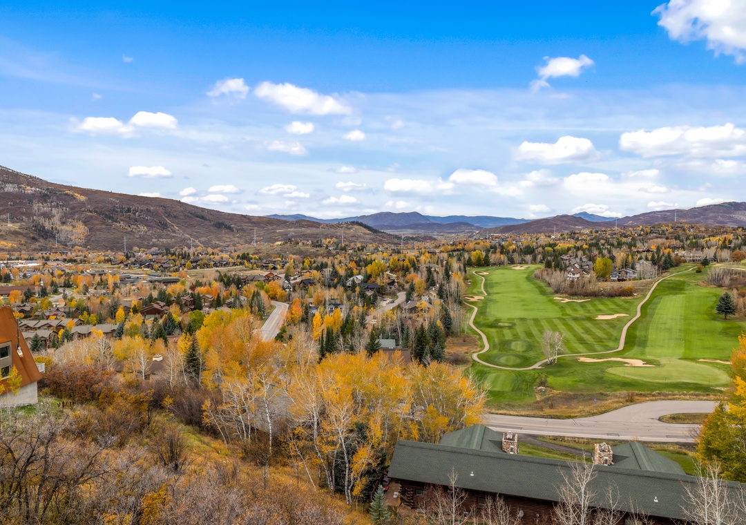 A mountain resort community in autumn, with a golf course winding through aspen groves painted in vibrant gold and orange.