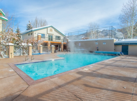 Plunge into heated waters with mountain peaks framing the horizon, while steam rises into crisp alpine air at this inviting outdoor pool.