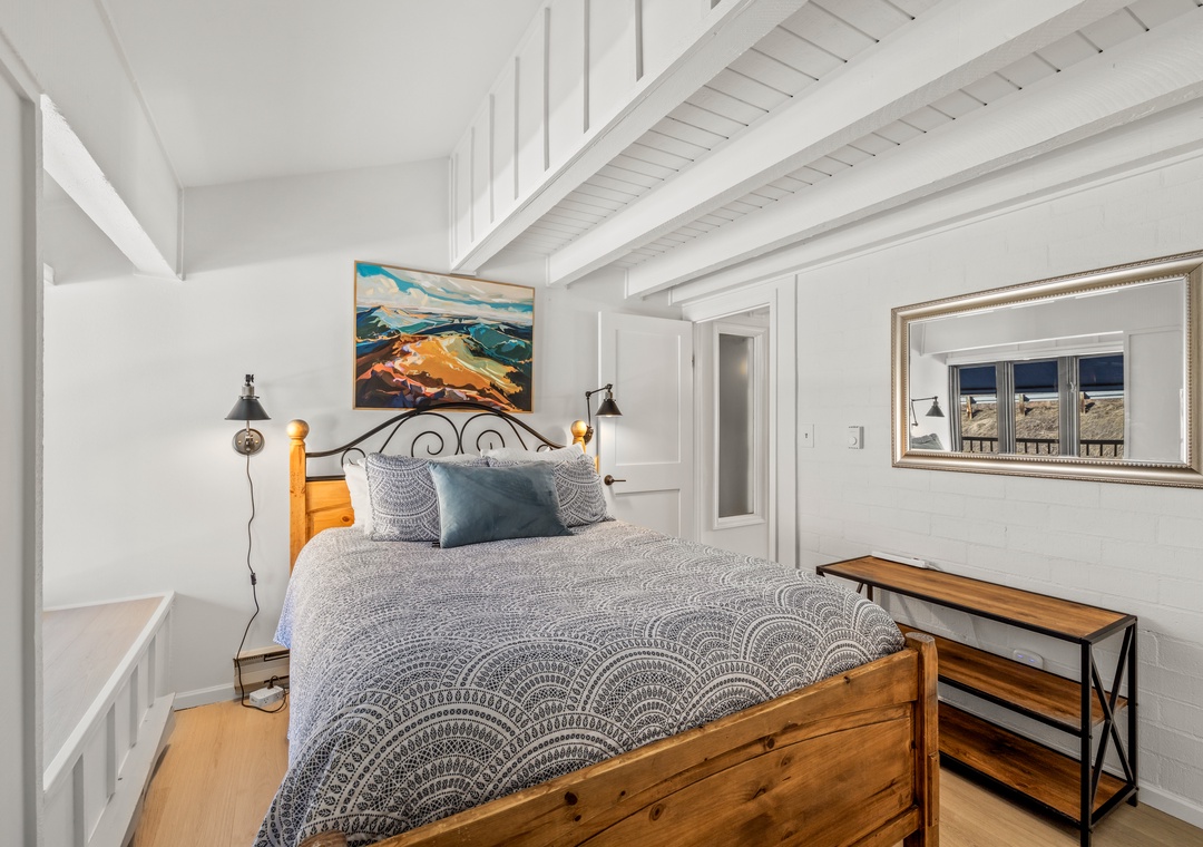 Drift off to sleep in this cozy bedroom with exposed beams, artful touches, and warm bedside lighting creating your perfect retreat.