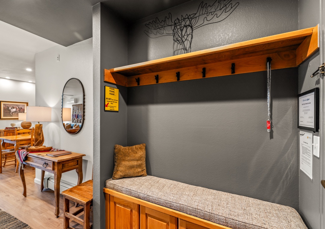 Cozy built-in entry way seating nook with warm wood details and hooks for your gear, perfect for settling in.