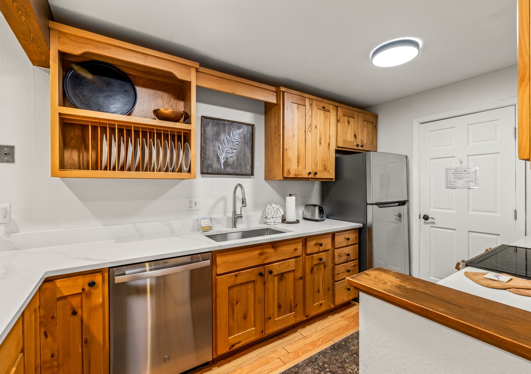 Cook your favorite meals in this fully equipped kitchen with warm pine cabinetry, marble countertops, and stainless appliances. Everything you need is here, from the built-in plate rack to dishwasher and full-size fridge.