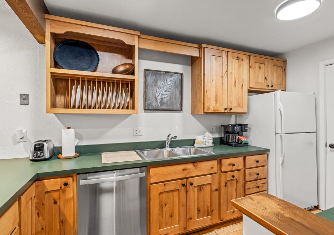 Cook your favorite meals in this fully equipped kitchen featuring warm wood cabinetry, and thoughtful touches like a plate rack.