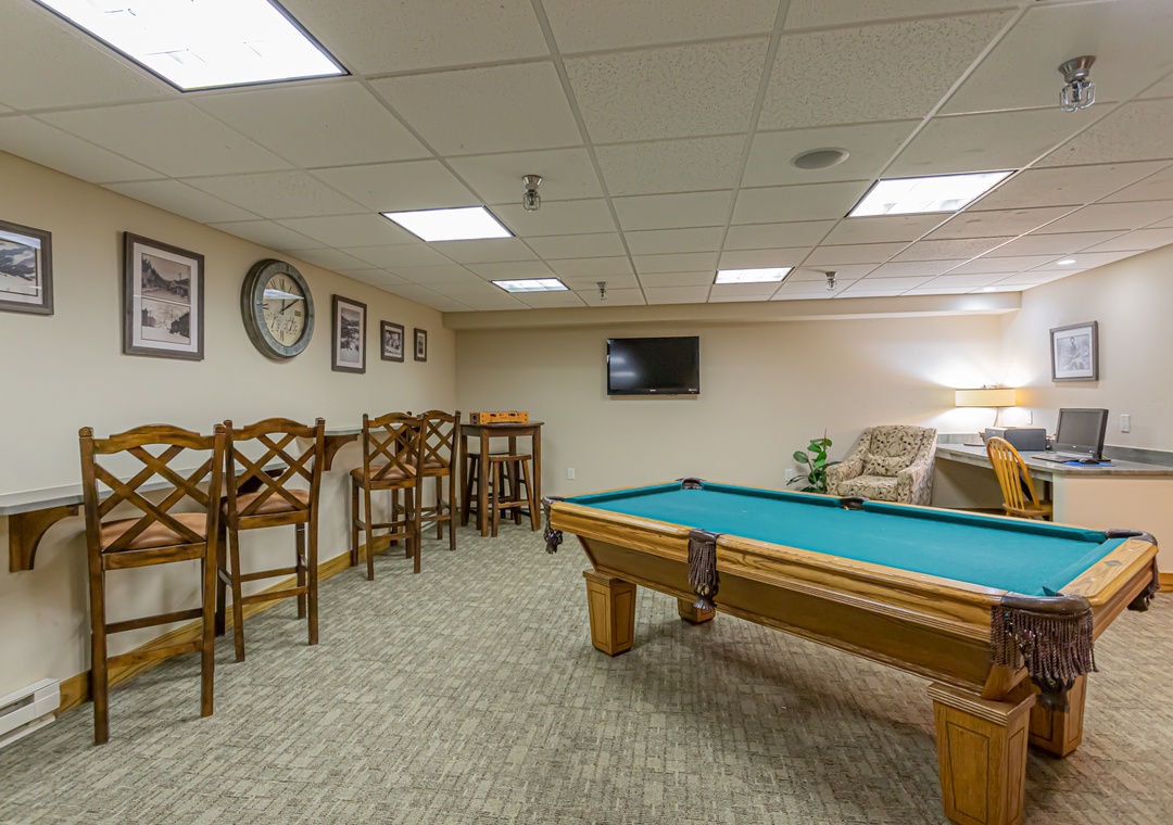 A welcoming game room with a billiards table, bar seating, and cozy seating area—perfect for unwinding and enjoying some friendly competition during your stay.
