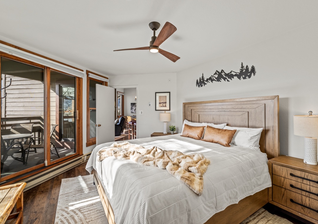 Your serene bedroom retreat features warm wood tones, cozy mountain decor, and private balcony access for peaceful mornings.