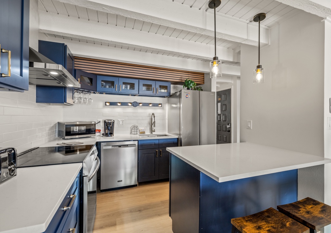 Your gourmet kitchen features navy cabinets, stainless appliances, and a spacious island perfect for cooking memorable meals during your stay.