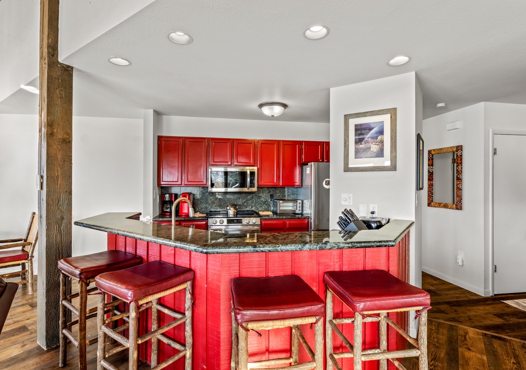 Your fully-equipped kitchen features vibrant red cabinets and granite counters, perfect for preparing meals during your stay.