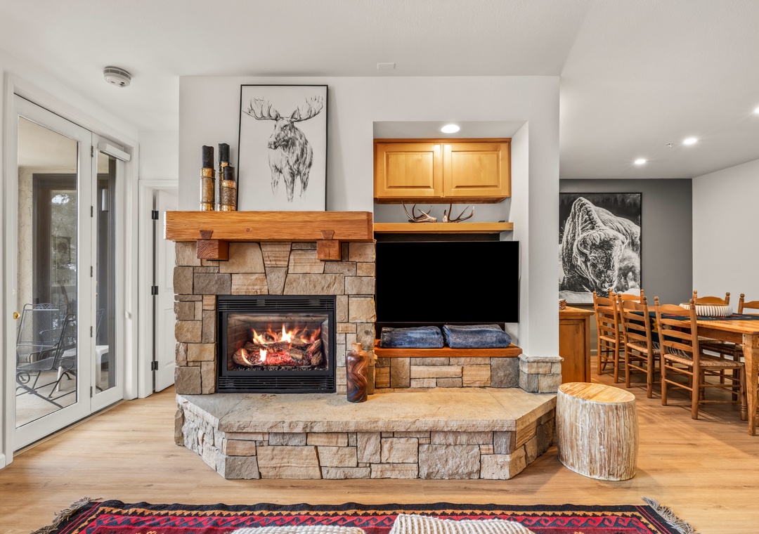 Cozy up by your crackling stone fireplace while enjoying mountain views through expansive windows in this inviting living space.
