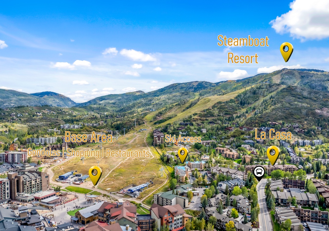 A panoramic view of a scenic mountain valley town featuring ski slopes, residential areas, and base facilities nestled among the foothills.