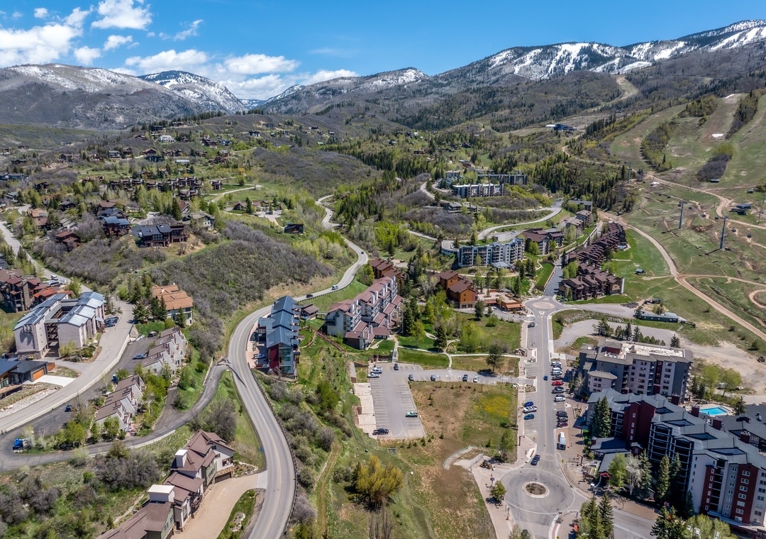A scenic mountain resort community nestled in a valley surrounded by snow-capped peaks and natural landscape, showcasing the property's location in a picturesque alpine setting.