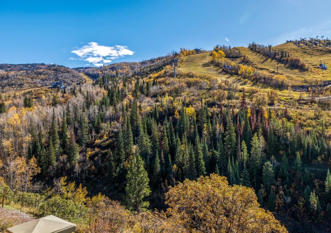 This property is nestled in the surrounding autumn landscape, where golden aspens and evergreen pines blanket the rolling hillsides beneath a crisp blue sky.