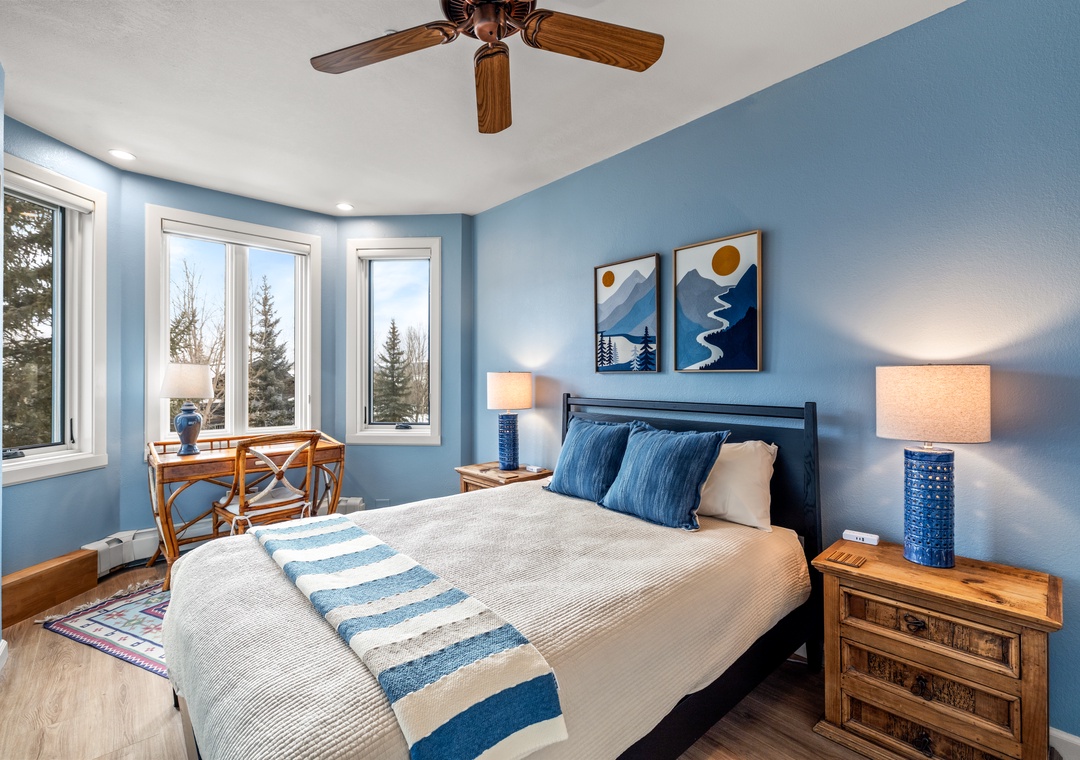 Drift off in your serene blue retreat where forest views through multiple windows create a peaceful sanctuary for restful nights.