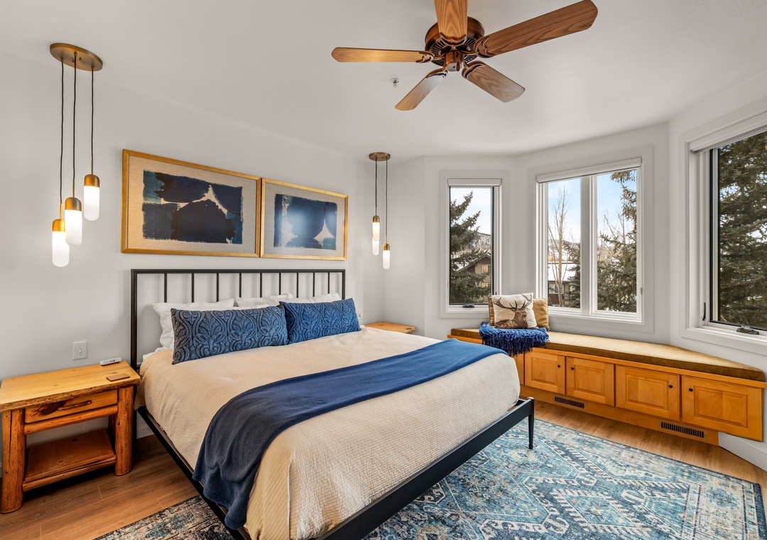 Wake up refreshed in your cozy Primary bedroom featuring a comfy bed, warm wood accents, and a peaceful window seat overlooking the trees.