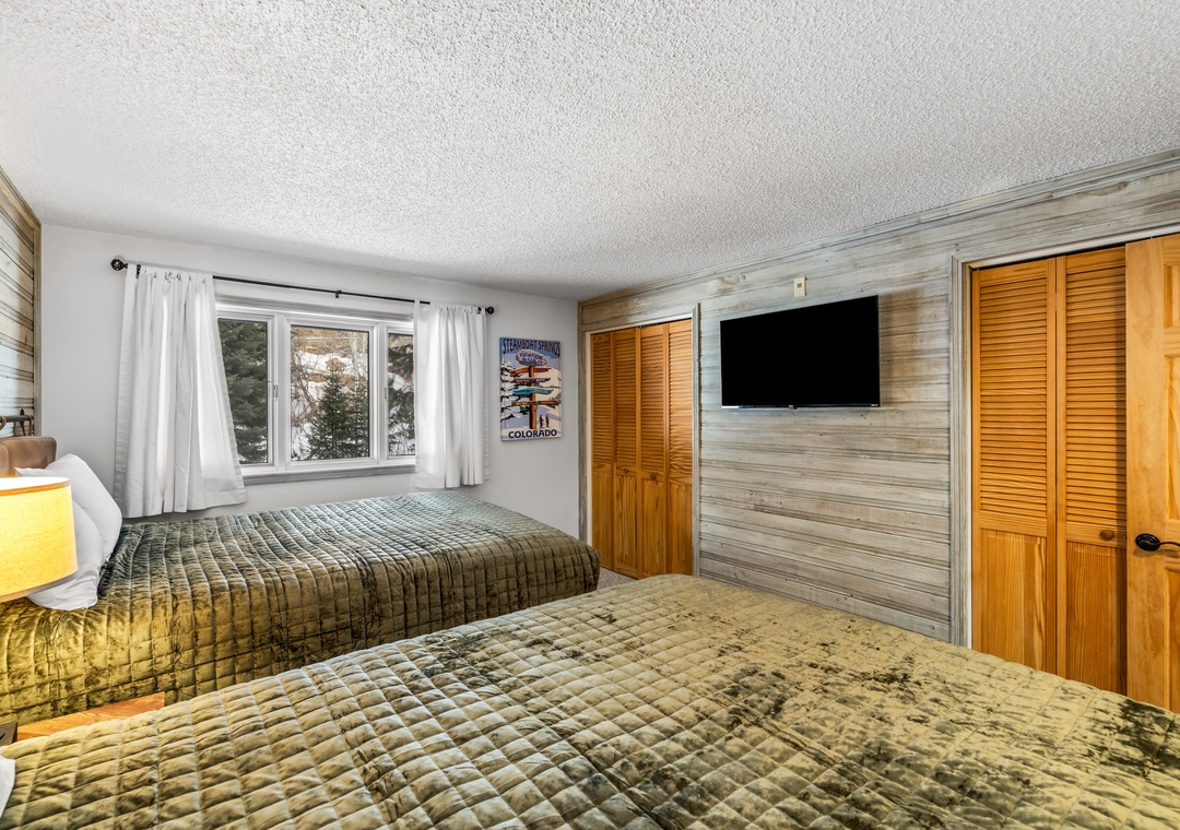 Relax in your cozy bedroom with twin beds, rustic wood accent wall, and mountain views from your window.