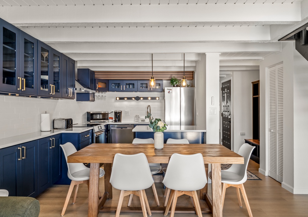 Your stunning open-plan kitchen features sleek navy cabinetry, modern appliances, and a warm wood dining table perfect for memorable meals.
