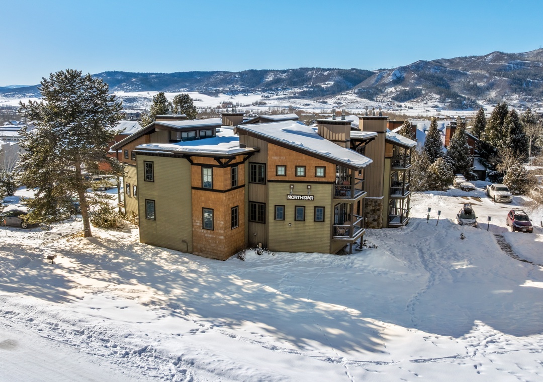 Vacation rental property nestled in snowy mountain surroundings, featuring multiple buildings with parking and scenic winter landscape views visible from the location.