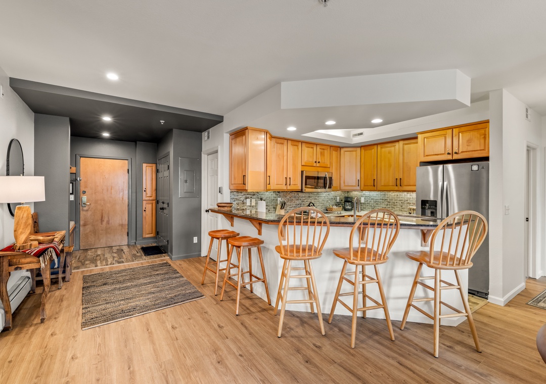 Your open-plan beautiful renovated kitchen welcomes you with warm wood cabinetry and stone counter tops, perfect for cooking and gathering around the breakfast bar.