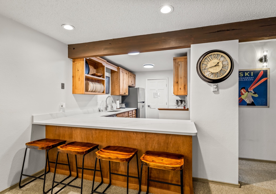 Gather around the breakfast bar for morning coffee or après-ski snacks in your fully-equipped kitchen, complete with warm wood accents, modern appliances, and mountain-inspired decor.