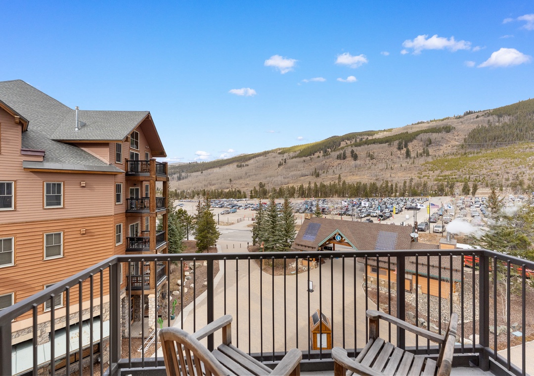 Mountain resort balcony overlooking the valley with outdoor seating and stunning mountain views.