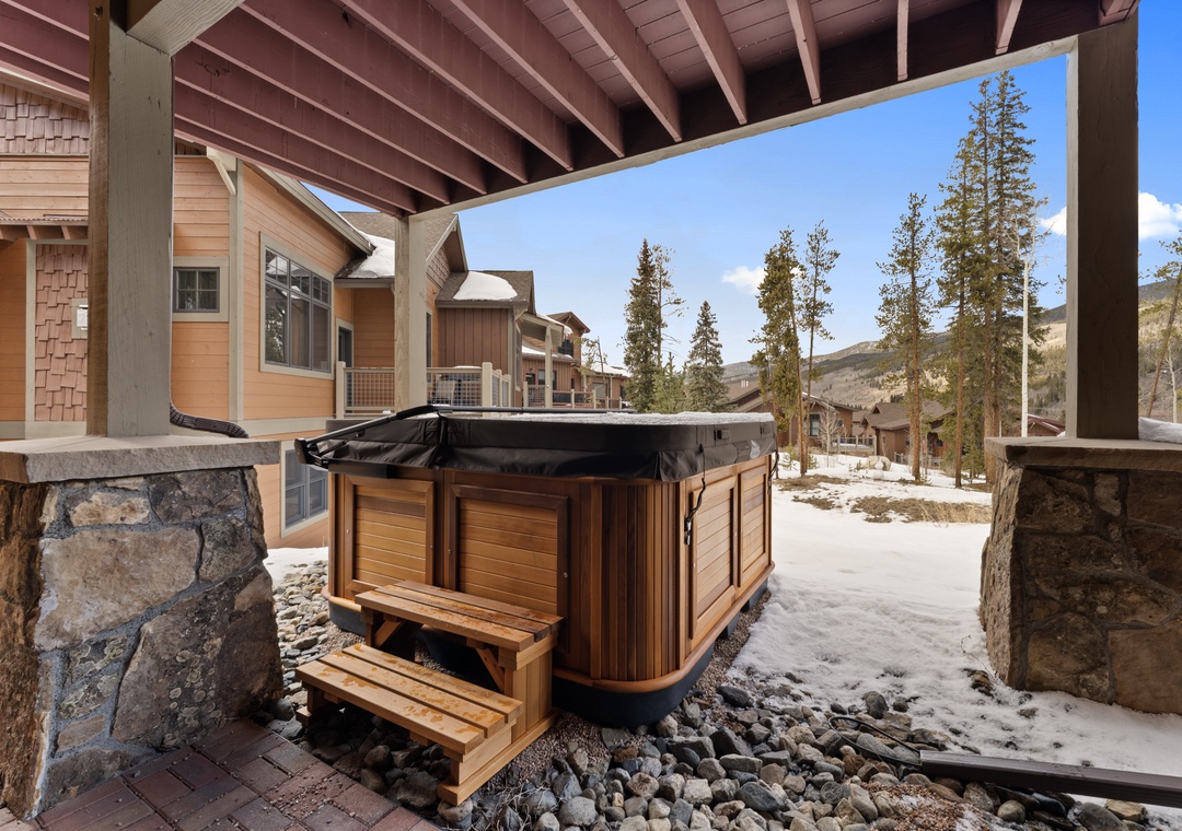 Your private hot tub awaits beneath a sheltered patio, framed by towering pines and mountain views—perfect for soaking away the day's adventures in crisp alpine air.