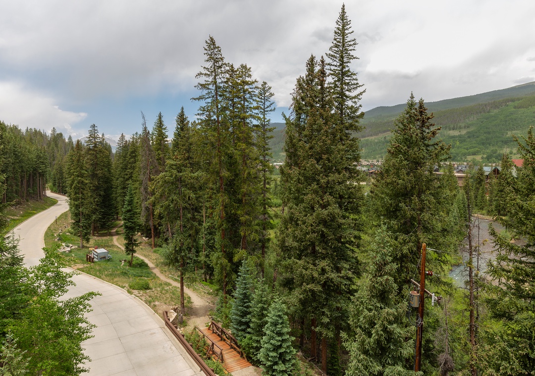 Scenic mountain valley setting with winding roads through pine forests leading to a charming village below.