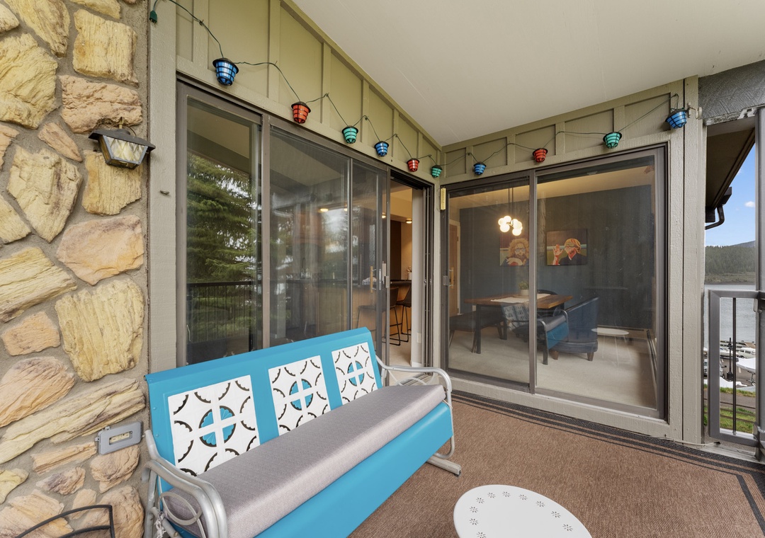 Step onto your private balcony and unwind on this cheerful blue seating while colorful string lights create magical ambiance for evening relaxation.