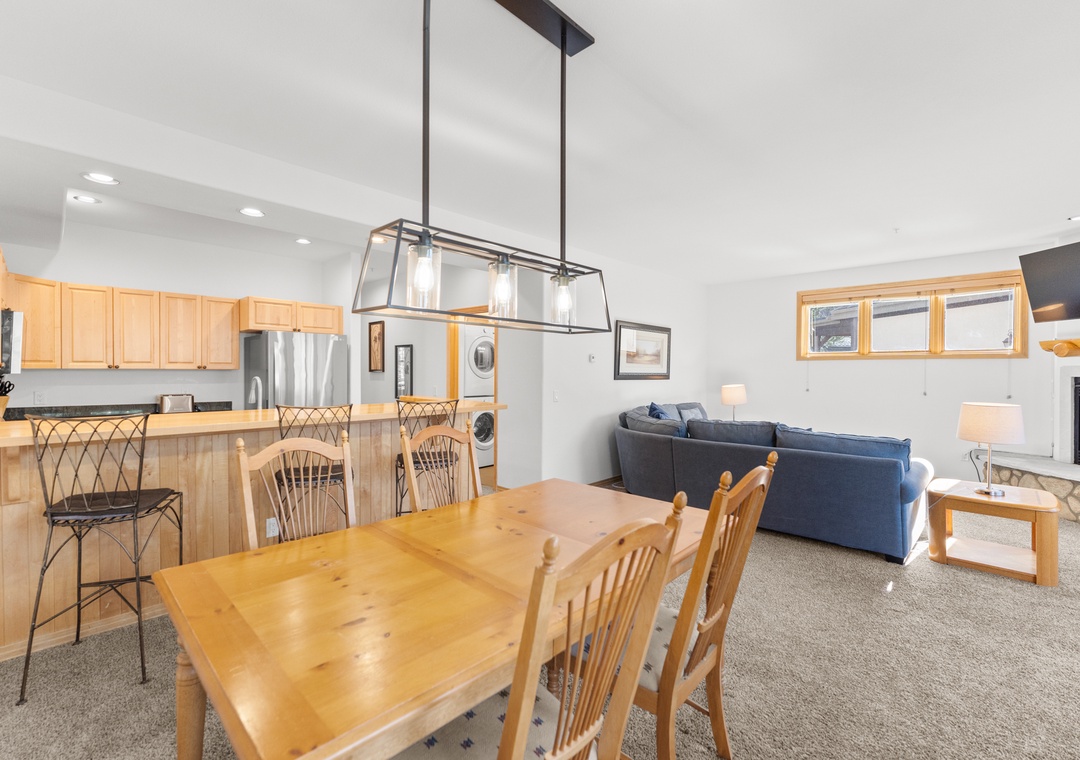 Relax in your spacious open-plan living area where natural wood accents and modern lighting create the perfect mountain retreat atmosphere.