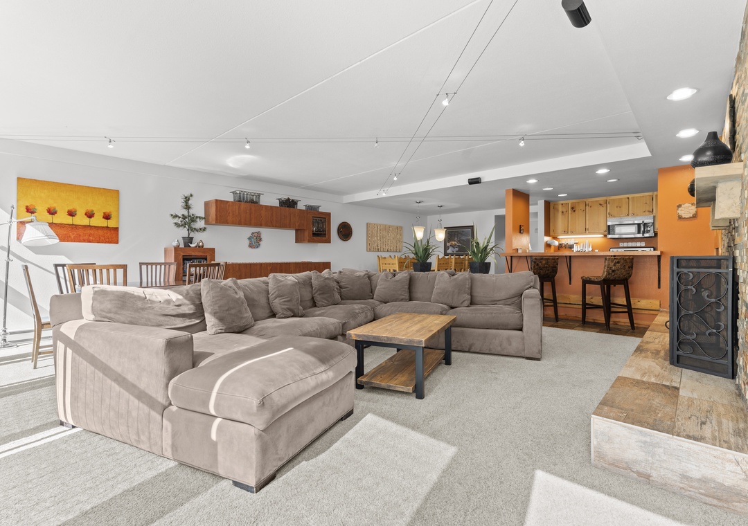 Gather here to share stories and laughter. This spacious open-concept area combines your living, dining, and kitchen, with plush seating, warm wood accents, and ample natural light.
